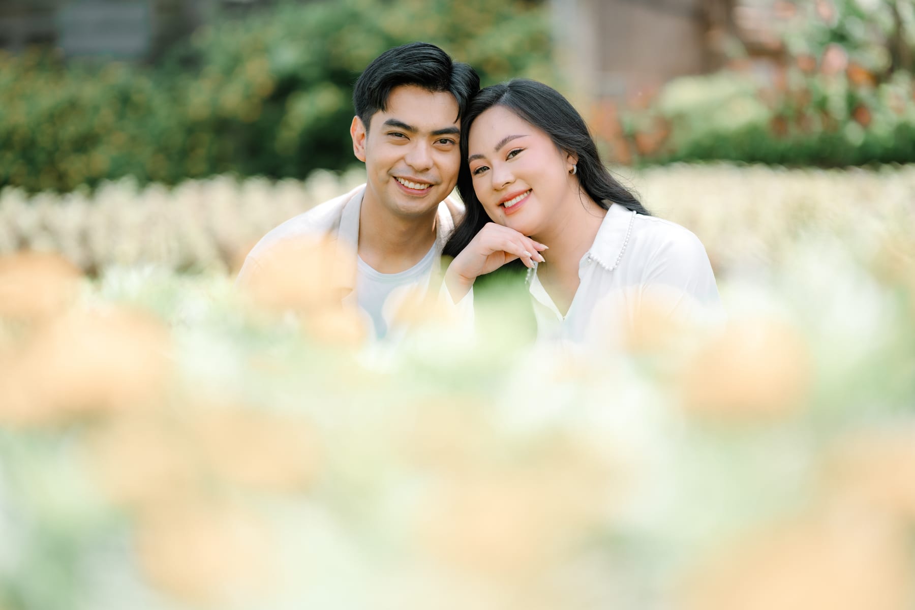 Luis and Tricia smiling behind the yellow blooms